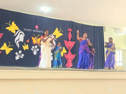 Women performing together on a stage decorated for a Women’s Day celebration.